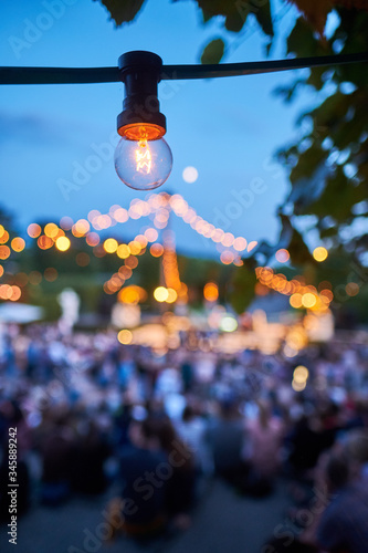 Detail einer Glühlampe bei einer großen Gartenparty. Stimmungsvolle Abendaufnahme-