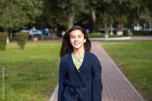 Pretty brunette little girl posing in autumn park background