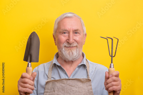 Senior gardener with garden tools copy space. Senior man holds garden tools.