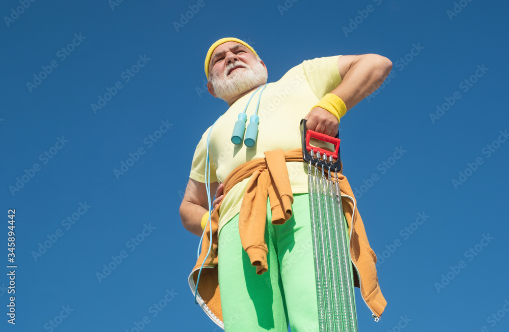 Fototapeta premium Grandfather sportsman on blue sky backgrounds. Funny sporty old sportsman finished his work out. Age is no excuse to slack on your health.