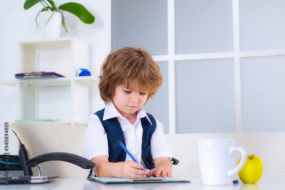 Young business boy. Portrait of a kid businessman on the modern office. Seriously young little children business man sitting in office.