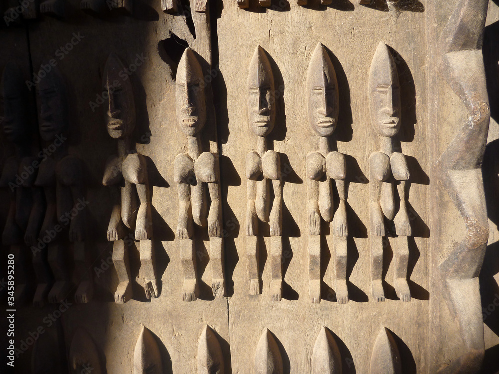 stara tradycyjna afrykańska płaskorzeźba na drewnianych drzwiach budynku w timbuktu przedstawiająca ludzkie postaci - obrazy, fototapety, plakaty 