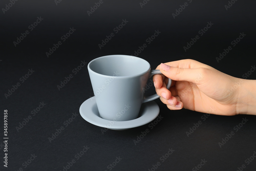 Female hand with blank cup on dark background Female hand with blank cup on dark background