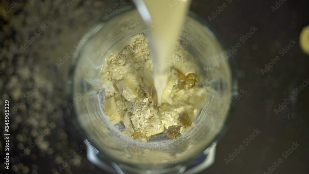 Milk is poured into a blender bowl with bananas and oatmeal. Smoothies in the mixer. Healthy food and drinks made from vegetables, fruits and berries. Milk is poured into a blender bowl with bananas and oatmeal. Smoothies in the mixer. Healthy food and drinks made from vegetables, fruits and berries.