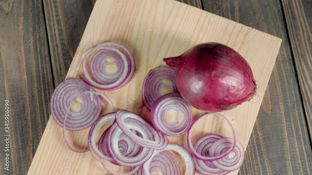 Camera moves up above peeled purple onion and sliced onion on a light board on wooden table. Concept of making fresh summer salad. Top view. Follow shot. 4K Camera moves up above peeled purple onion and sliced onion on a light board on wooden table. Concept of making fresh summer salad. Top view. Follow shot. 4K