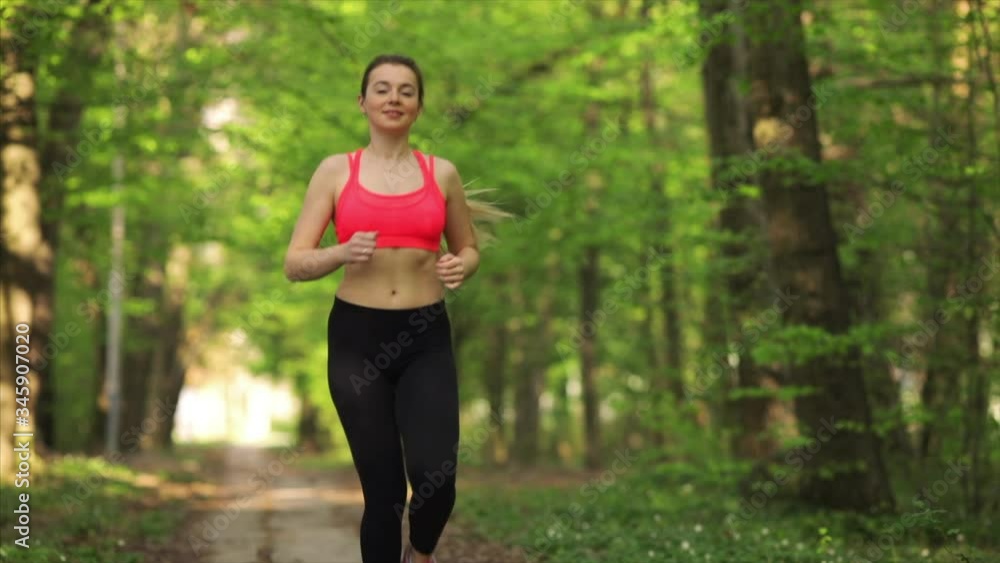 Athlete woman jogging in park at sunset. Tired female runner breathing hard at outdoor training. Sport woman at morning workout. 