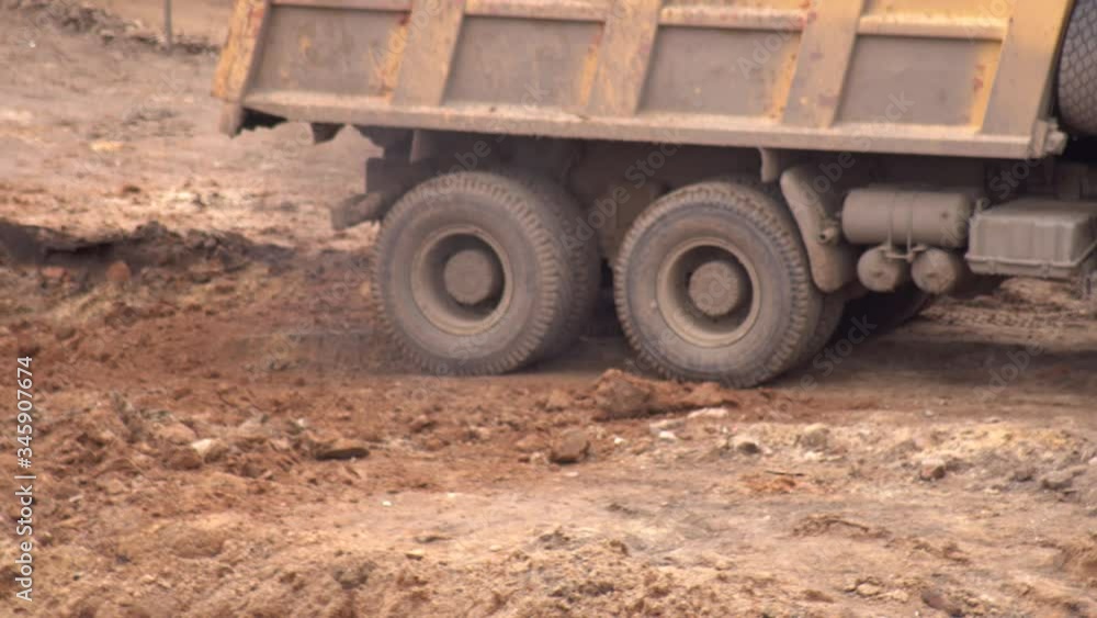 A truck loaded with sand drives off after loading an excavator with sand at a construction site, industry. Copy space A truck loaded with sand drives off after loading an excavator with sand at a construction site, industry. Copy space