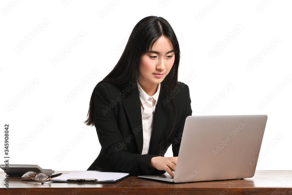 Beautiful Asian secretary at table against white background Beautiful Asian secretary at table against white background