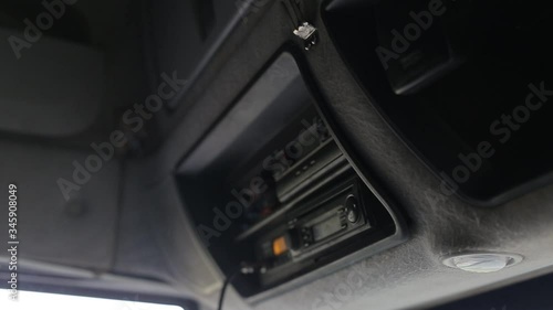 The truck driver takes off his hand radio for communication in the channel. Truck interface inside the cab, tachograph for working hours, labor and rest photo