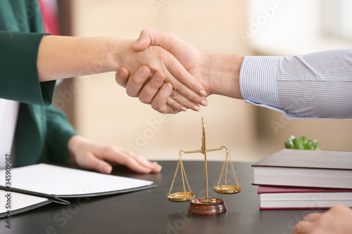Female judge and client shaking hands in office, closeup photo