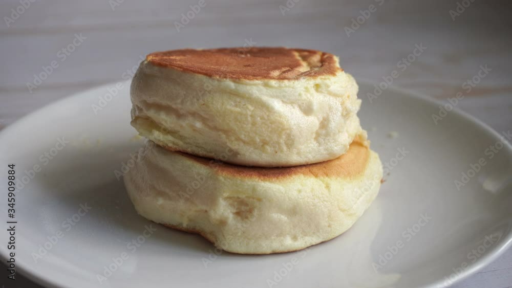 fluffy souffle pancakes stack on the white plate pouring with the syrup fluffy souffle pancakes stack on the white plate pouring with the syrup