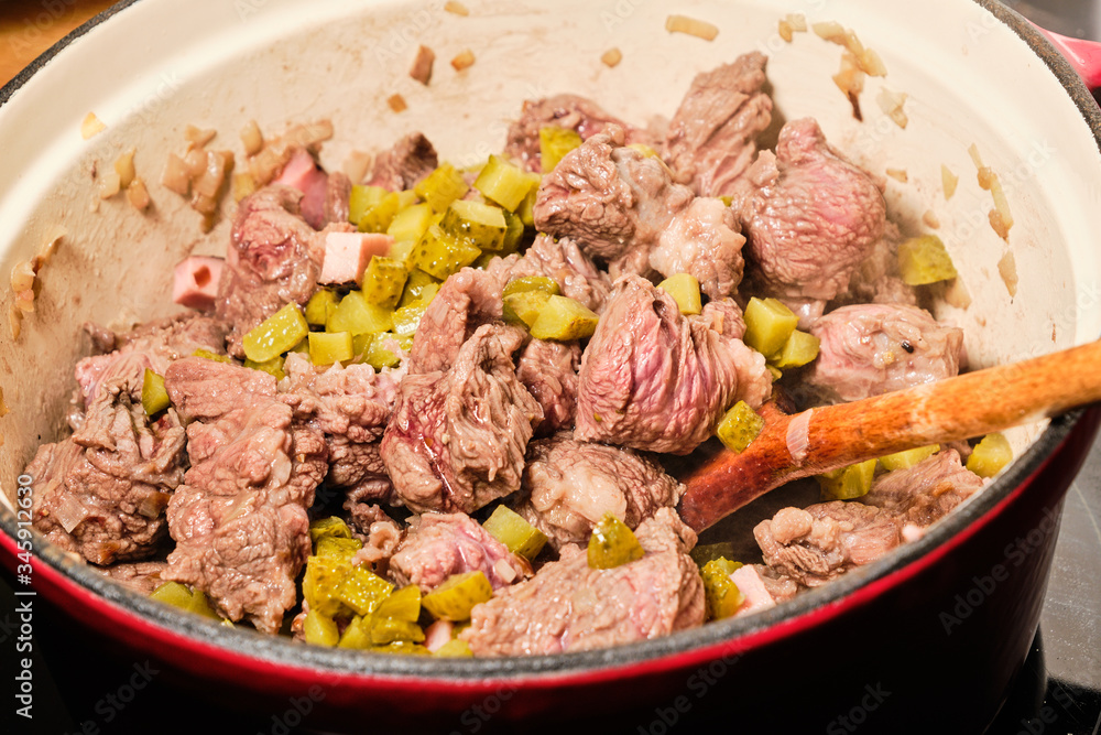 Preparing meat with sliced pickles for znojemska sauce in cooking pot Preparing meat with sliced pickles for znojemska sauce in cooking pot