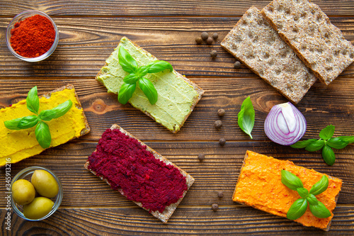 Tasty hummus snack, assorment of paprika, avocado, beetroot and curry hummus on rustic brown background. photo