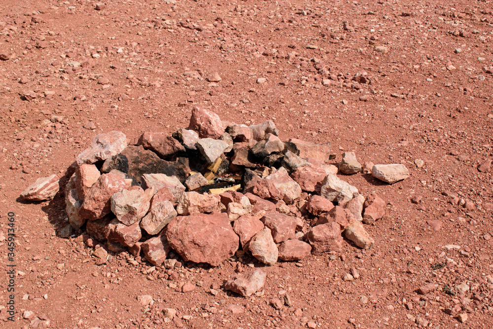 Campfire in the desert. Charred stones are stacked in a circle. Brown color with a red tinge of rock and surface. Concept of a bonfire in a remote area, a journey along Mars.
