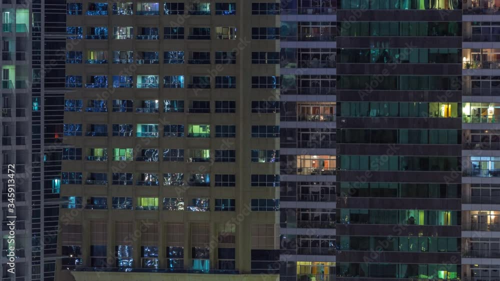 Rows of glowing windows with people in the interior of apartment buildings at night. Modern skyscrapers with glass surface. Concept for business and modern life Rows of glowing windows with people in the interior of apartment buildings at night. Modern skyscrapers with glass surface. Concept for business and modern life