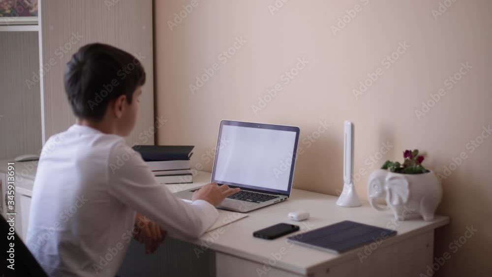 Schoolboy study at desk in his room. Boy use laptop for lessons. Books and tablet on the table. Study home during qurantine Schoolboy study at desk in his room. Boy use laptop for lessons. Books and tablet on the table. Study home during qurantine