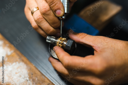 Master goldsmith while working on jewelry on the of work table.