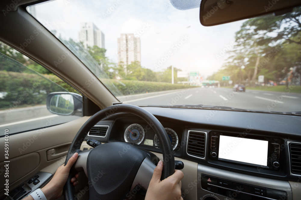 People hands holding steering wheel while driving car on city road