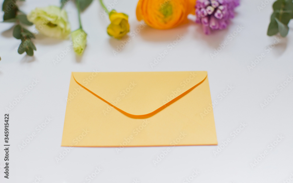 Yellow envelope and floral border of pink and orange ranunculus, hyacinth and eucalyptus on a white background Yellow envelope and floral border of pink and orange ranunculus, hyacinth and eucalyptus on a white background