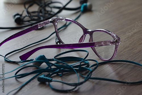 glasses and headphones with a tangled cable on the table