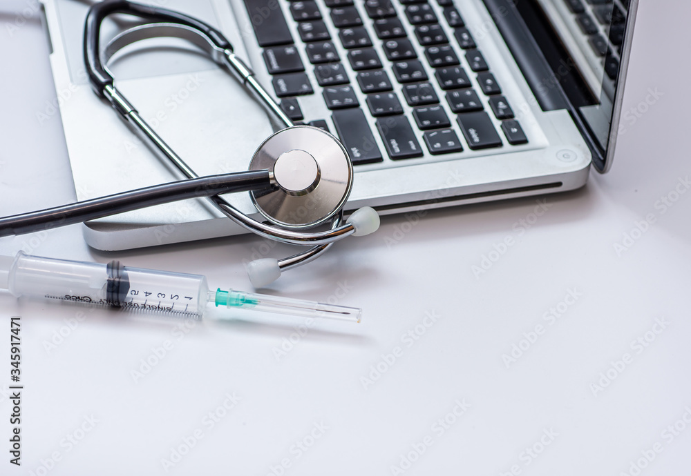 Stethoscope and syringe on laptop, Health care cost concept, copy space Stethoscope and syringe on laptop, Health care cost concept, copy space