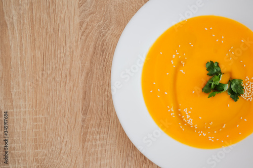 Healthy food, Diet, Detox, Clean Eating or Vegetarian concept. bright delicious pumpkin soup puree, poured with oil and sprinkled with sesame seeds. stands on a wooden table