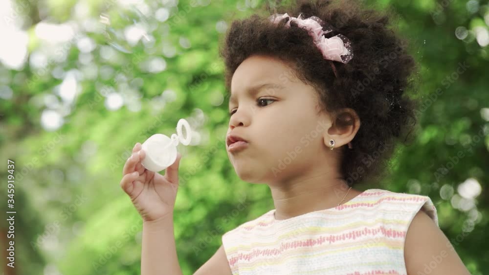 Close up of african-american girl blow soap bubbles in the park. Close up of african-american girl blow soap bubbles in the park.
