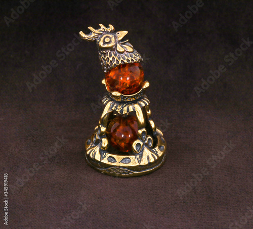 Amber souvenir. A miniature metal bell with an amber element. Background is dark brown or white (isolated image).