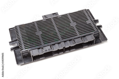 Back of the electronic control unit is made of black plastic with a microcircuit inside and mounts on a white isolated background in a photo studio. Spare part for replacement when repairing car.