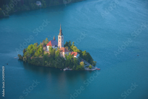 Fototapeta Naklejka Na Ścianę i Meble -  Aerial view of Lake Bled and Julian Alps, with lake island and charming little church dedicated to the Assumption of Mary, famous tourist attraction in Slovenia