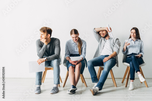 Group of employees with resume sitting on chairs in office