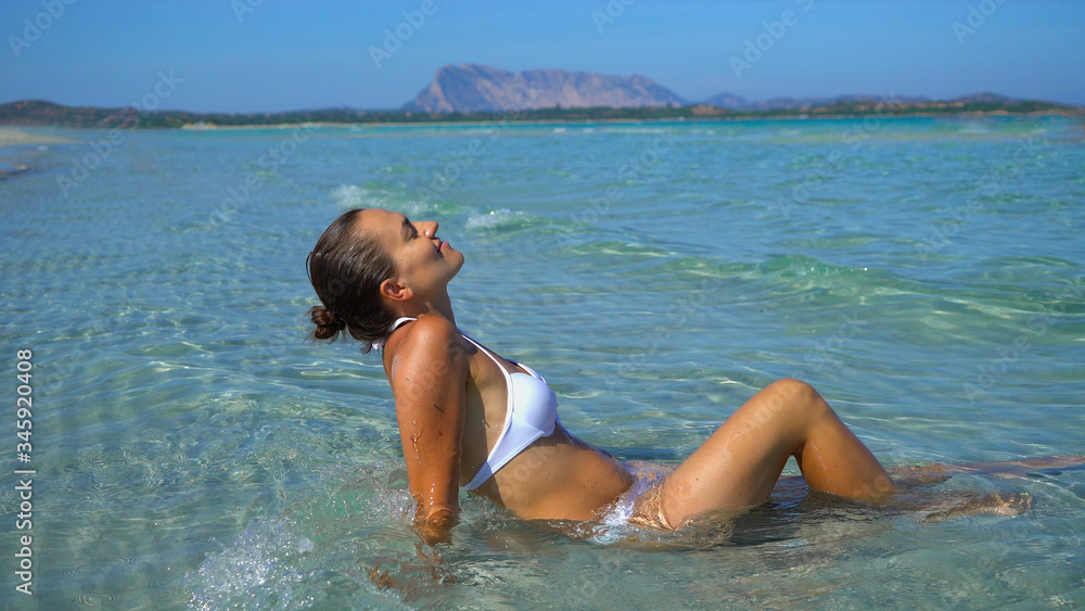 Happy woman in bikini sunbathing by turquoise sea, Sardinia, Italy, La Cinta beach Happy woman in bikini sunbathing by turquoise sea, Sardinia, Italy, La Cinta beach