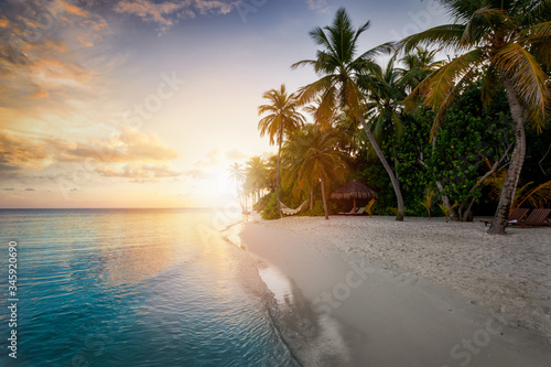 Sonnenuntergang hinter einem tropischen Strand mit Palmen und t  rkisem Meer