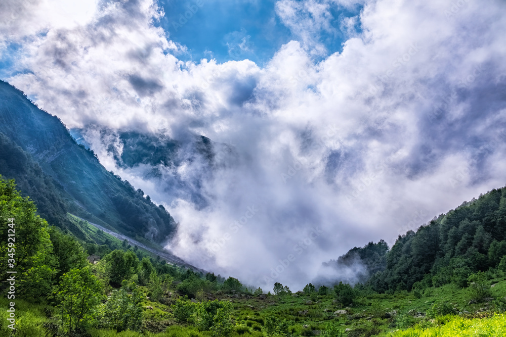 Heavy fog and clouds in mountain gorge in the summer or spring. A layer of melting snow in the summer in high mountains.