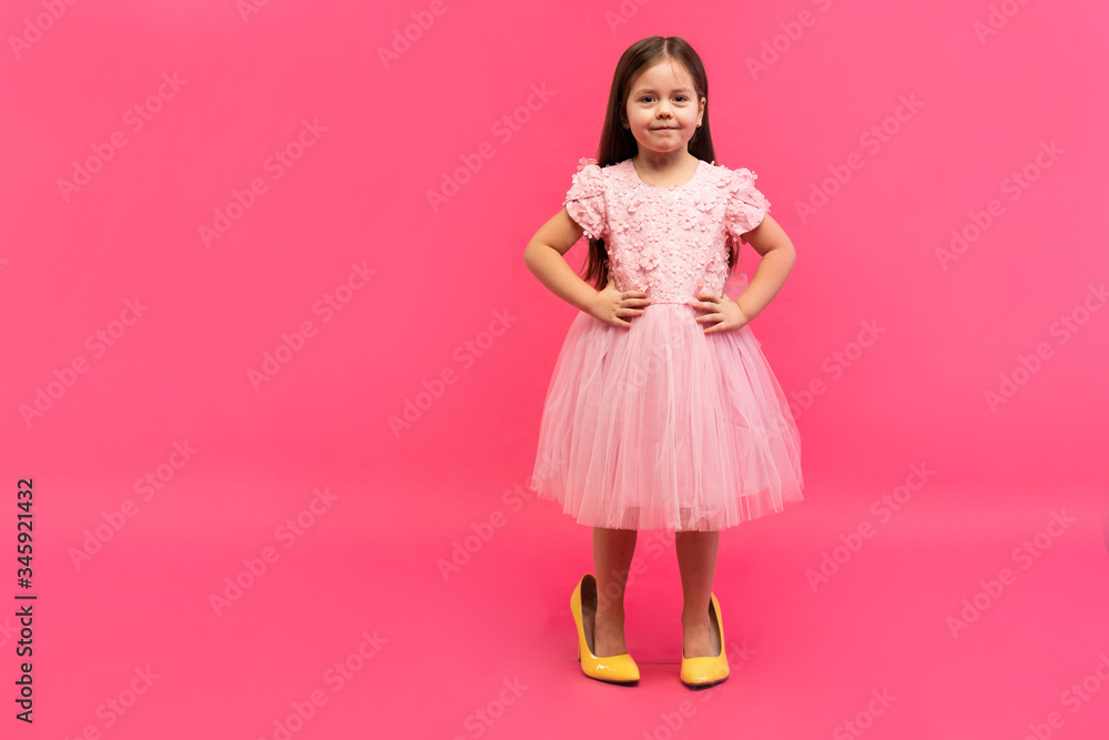 Fashionable cute young girl in big mother's yellow shoes on colored background. Fashionable cute young girl in big mother's yellow shoes on colored background.