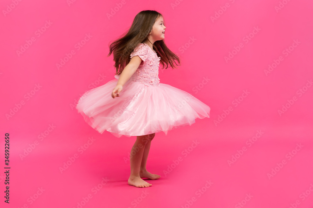 Cute little girl dreams of becoming a ballerina. Little Dancing Girl. Studio Shoot Over Pink Background Cute little girl dreams of becoming a ballerina. Little Dancing Girl. Studio Shoot Over Pink Background
