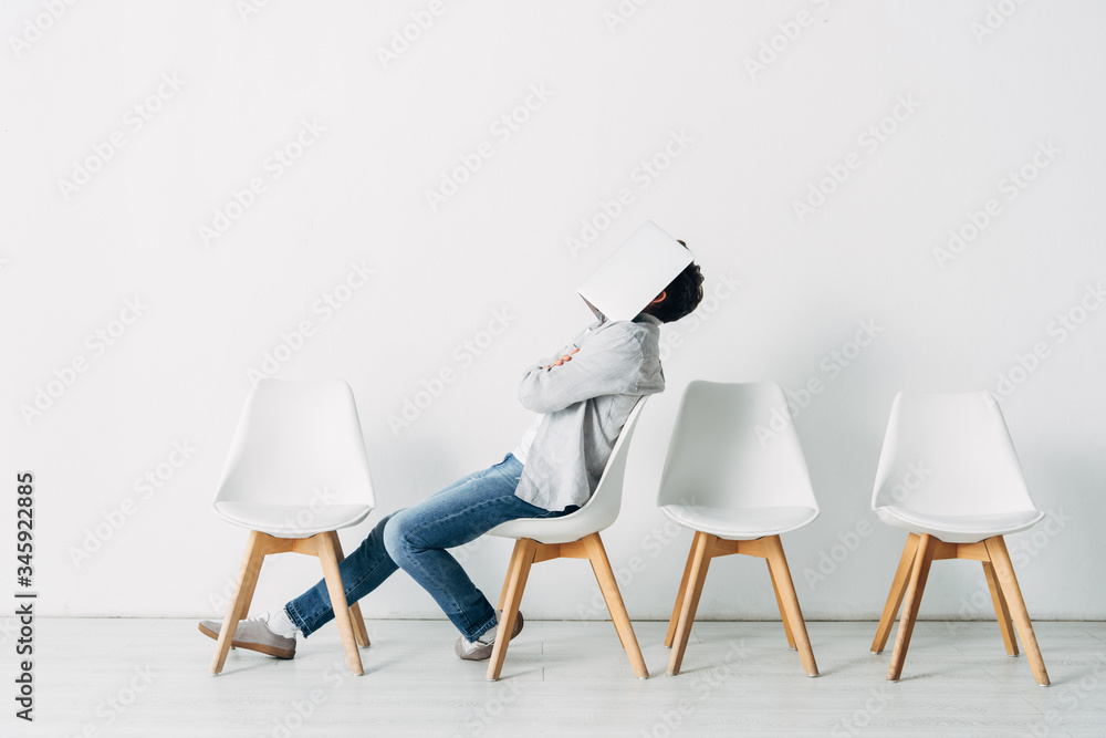 Fototapeta premium Side view of employee with crossed arms covering face with laptop on chair
