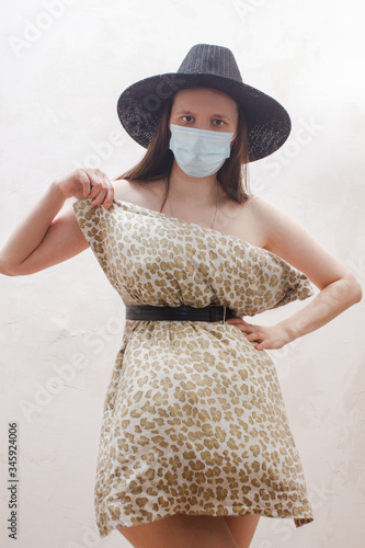 Woman in medical mask,  pillow dress and summer hat. Fashion girl. Pillow Challenge due to home isolation. Caronavirus Quarantine. photo