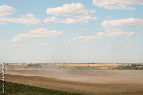 Dust storm on the field in Ukraine on the background of the village. Copy space.