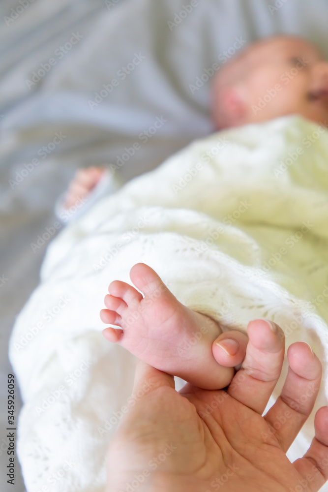 Close-up newborn foot of baby laying on the bed in mother hand Close-up newborn foot of baby laying on the bed in mother hand