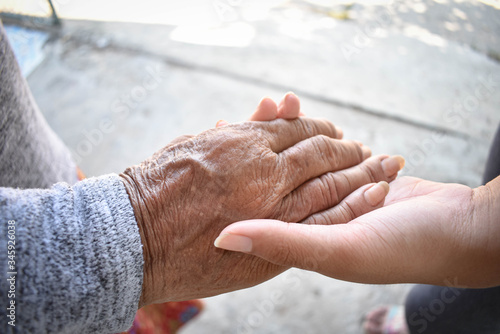 Hands of two people represent family warmth and care for the elderly.