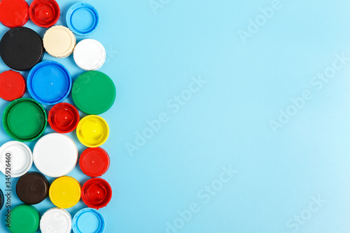  Multi-colored plastic bottle caps on a blue background. The problem of environmental pollution. Recycling plastic. Top view, copy space.
