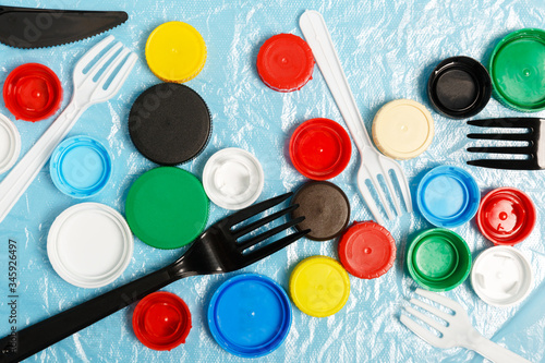 Wallpaper Mural  Multi-colored plastic bottle caps and plastic forks on a plastic bag. The problem of environmental pollution. Recycling plastic. Top view, flat lay. Torontodigital.ca
