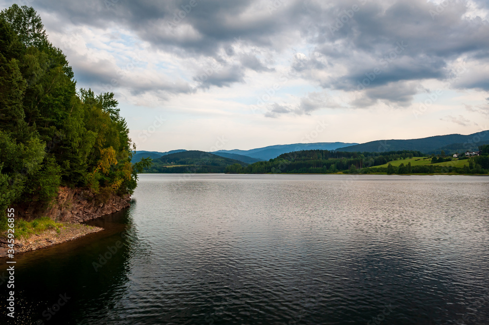 Sunset at the lake. Evening at pond with cloudy stormy sky. Sumava, Bohemian Forest, Böhmerwald, Czech Republic.