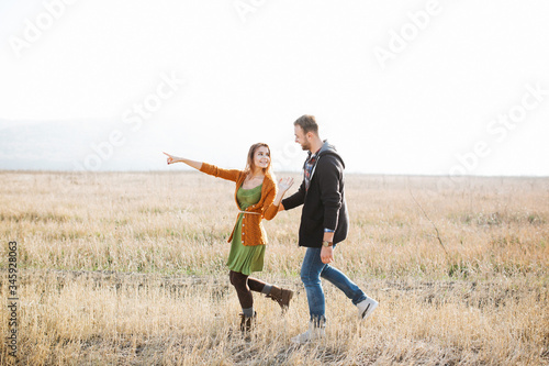 Happy young couple of man and woman walking outdoors in a field.
