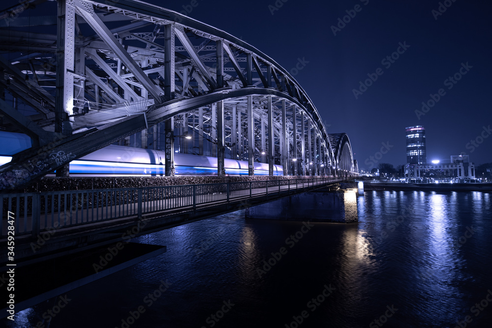 ICE Zug fährt nachts über die Hohenzollernbrücke in Köln ein