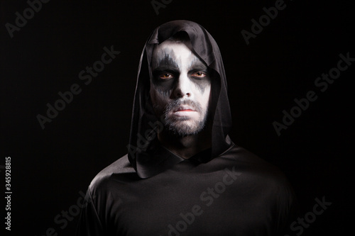 Portrait of man wearing demon make up for halloween party isolated over black background.