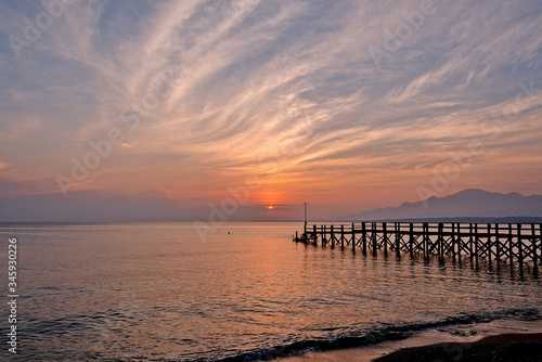 Sunset over the sea and a black wooden pier