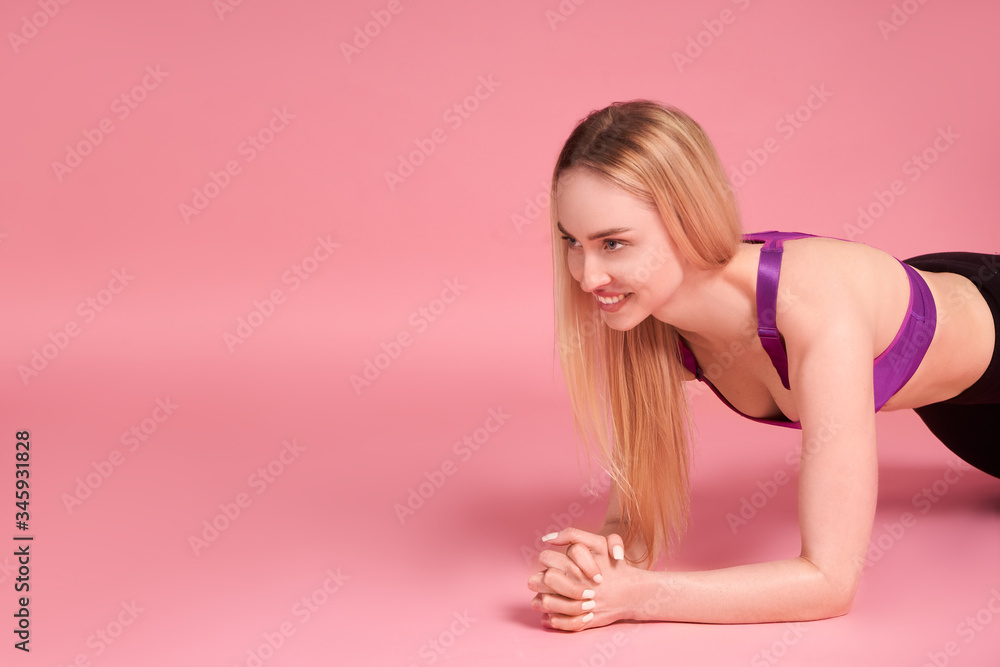 Fitness girl doing exercise board on pink studio background Fitness girl doing exercise board on pink studio background