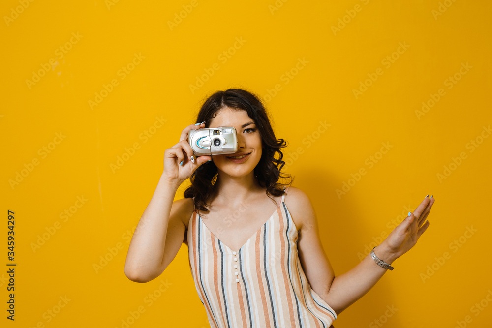 Obraz premium Image of a beautiful Asian woman taking a photo with a retro camera and show gestures isolated over yellow background